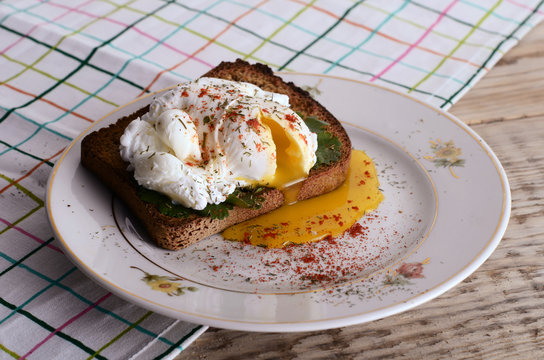 eggs pashot on a toast on a wooden table