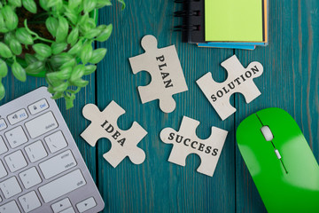 Puzzle pieces with words "idea", "plan", "solution", "success", sketchbook, computer keyboard