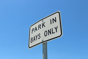 black and white Park in Bays Only sign in blue sky background