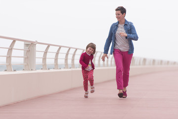 Obraz premium mother and cute little girl on the promenade by the sea
