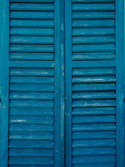 Wooden window shutters in blue. Antique homemade shutters on the windows.