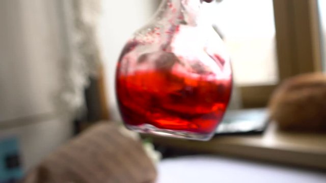 Man's hand turns the flask with red chemical