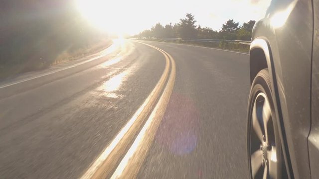CLOSE UP: Driving through the curve on steep coastal road descending from the mountain ridge towards the North Atlantic Ocean on sunny day. People traveling on switchback highway to the Canadian coast
