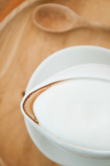 Close-up shot of white latte foam on wooden table.