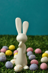 A white plastic bunny figurine displayed with speckled easter eggs