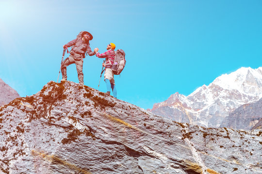 Two People shaking Hands on Mountain Summit