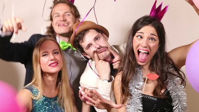 Two cute young couples making funny faces in party photo booth 