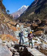 Two Hikers Man and Woman crossing wooden Bridge in Mountains