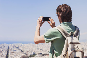 Traveler man taking pictures of a big city on his smart phone, travel and active lifestyle concept