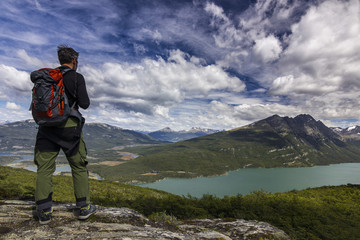 Fototapeta na wymiar man with backpack standing on the cliff in mountains at above lake