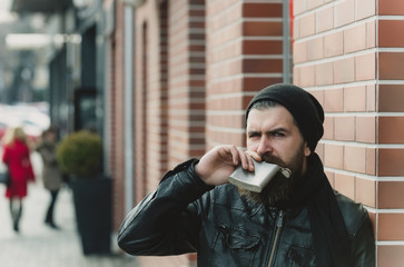 serious bearded man hipster with metallic jar in leather jacket