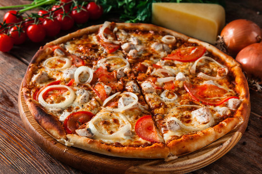 Fresh baked pizza served on wooden background with ingredients. Restaurant menu photo.