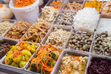 Korean snacks and salads on display in trays on the market.