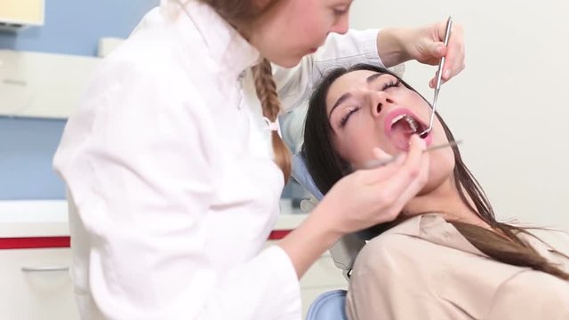 Close up of female dentist examining aching tooth of attractive female patient
