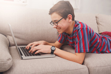 Teenage boy using laptop on couch at home