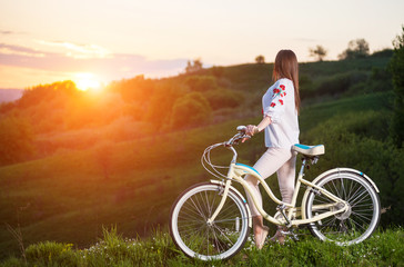 Obraz premium Woman with retro bike on the hill in the evening