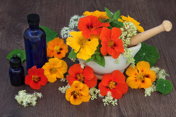Healing Flowers and Herbs. With aromatherapy essential oil bottles and edible flowers in a mortar with pestle.