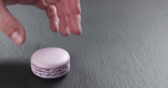 Slow motion of man hand stacking lavender violet macarons on slate board, 4k 60fps prores footage