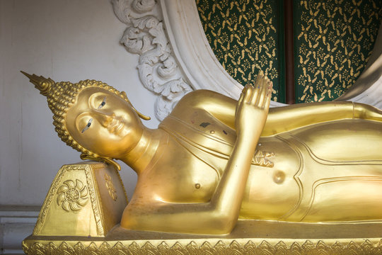 Golden reclining Buddha statue in buddhist temple in Thailand, symbol of peace and serenity