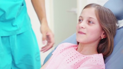 Little girl shaking hands with dentist while sitting in the chair, graded