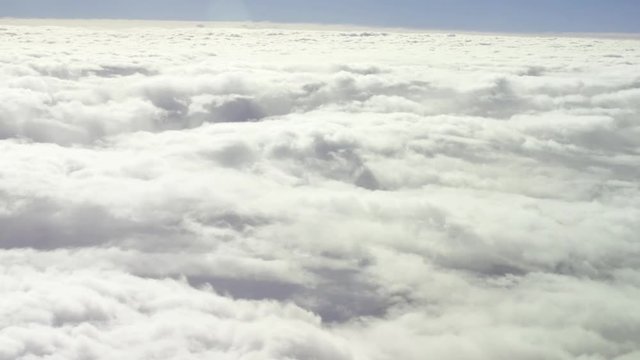 General view from the airplane window during a flight to fluffy thick clouds. Aerial shot. Traveling by air.