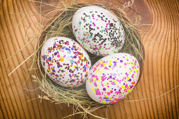 Colorful painted easter eggs in brown basket. top view