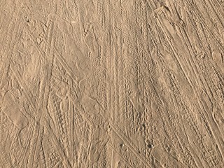 Soil ground with wheel tracks, dog paws and slippers printed. Background and texture.