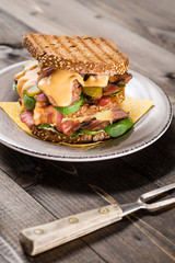 Big Homemade Sandwich with Roast Beef, Bacon, Pickles, Baby Spinach and Coleslaw Dressing in Toasted Bread