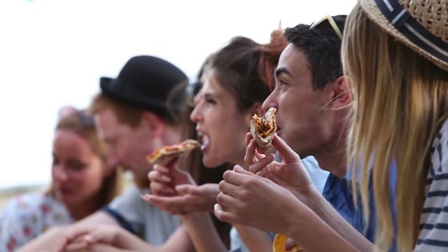 Close up of group of young multi-ethnic friends enjoying at a party while eating pizza