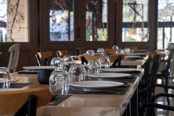 Horizontal image of modern restaurant with wooden tables with plates and glasses