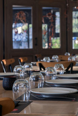 Vertical image of modern restaurant with wooden tables with plates and glasses