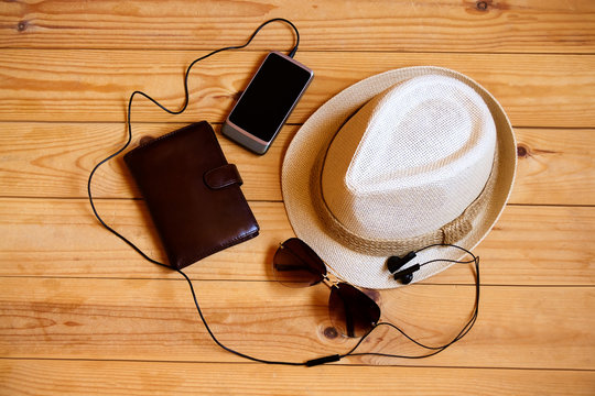 Hat, wallet, smartphone, headphones  and sunglasses on wooden background. Relaxation or vacation concept