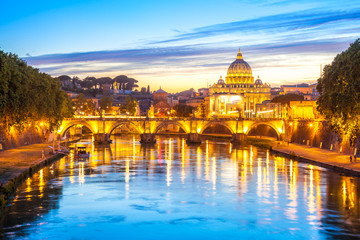 Fototapeta na wymiar Cityscape of Rome at twilight with San Pietro cathedral, Sant'Angelo bridge and Tevere river illuminated by city lights of Roma in Italy