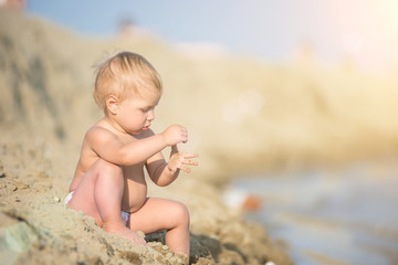 Baby playing with toys on the sandy beach near the sea. Cute little kid in  sand on tropical beach. Ocean coast.