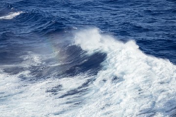 Spray rainbow of the deep ocean waves