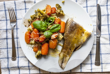 Bass baked with broccoli, carrots and basil leaves