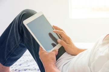 Closeup of Male Hand wear Jeans use Wireless Digital Tablet PC on Bed
