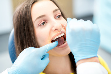 Professional teeth cleaning with dental floss at the dental office. Close-up view on the woman's...