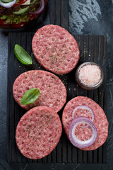 Close-up of raw burger cutlets made of ground beef meat, above view, studio shot