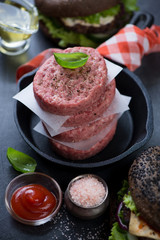 Frying pan with a stack of fresh uncooked beef burger cutlets, studio shot