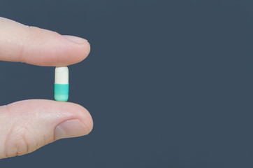 Tablet capsule medicine in fingers close-up