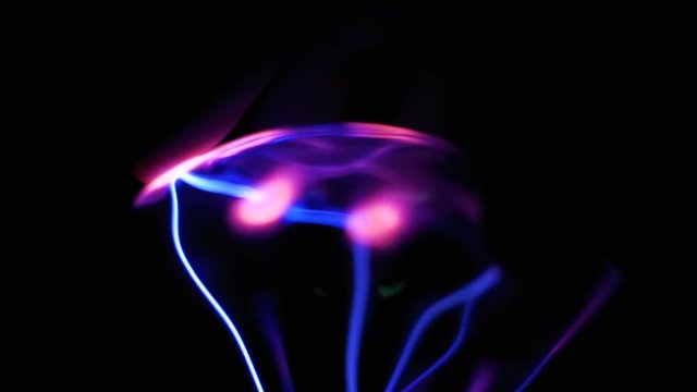 Close-up view of plasma ball with moving energy rays inside on black background. Slow Motion in 96 fps. Plasma Ball And Lightning. High voltage. Tesla generator. Electric ball on black background.