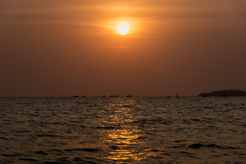 Fototapeta premium Sun setting a fishing boats head out to sea.