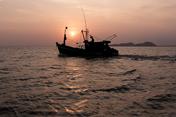 Setting sun behind a fishing boat.