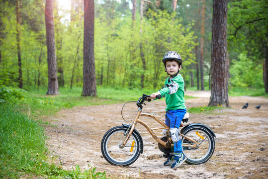 Happy cute blond kid boy having fun his first bike on sunny summ