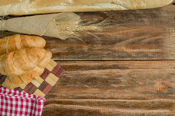 Freshly baked delicious bread on a rustic wooden background with copy space, flat lay..