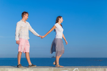 Fototapeta na wymiar Attractive couple walking along concrete pier