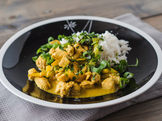 Delicious turkey mango curry with rice on a black plate