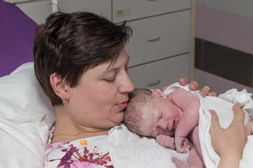 Happy mature woman, mother, with newborn baby immediately after delivery. © hypotekyfidler.cz