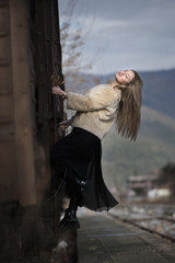 Naklejka premium Blond young woman wear sheep jacket and black long skirt climbed on a wagon train
